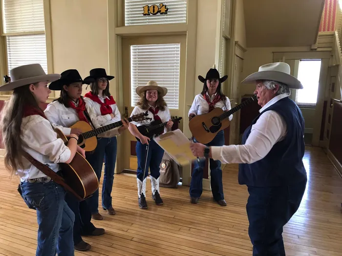 Judy James coaching young Cowtown Opry Buckaroos performers with guitars